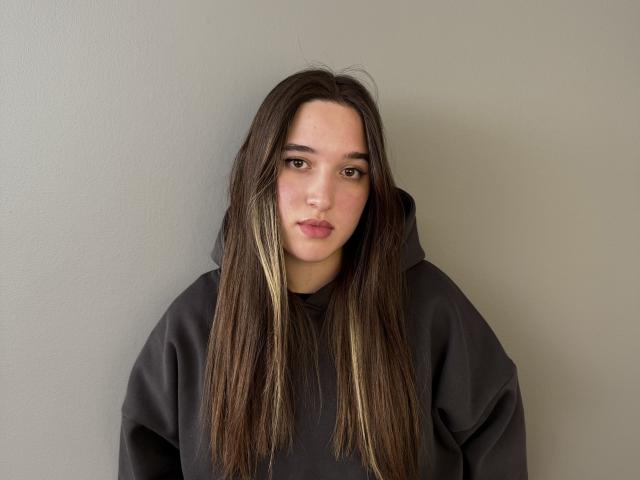 SherieStoneback tiene el cabello largo y castaño con reflejos rubios, y lleva una sudadera gris oscuro. Está mirando directamente a la cámara con una expresión neutra. Su rostro está ligeramente enrojecido..
