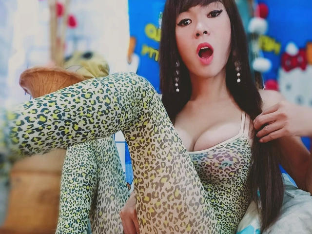 SuperiorMistress - sensual, com calças de lycra estampadas de leopardo, seios médios e uma expressão de surpresa com a boca aberta, sentada com uma perna levantada, cabelo preto longo e brincos pendurados..