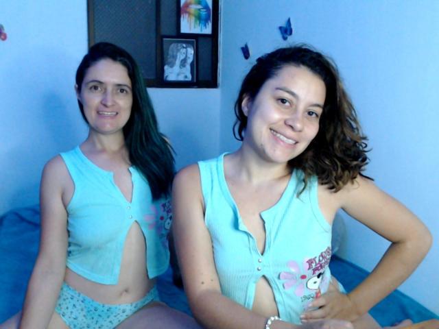 LunaVenus tem dois seios, vestindo croppeds azuis claros combinando e calcinhas estampadas, sentada em uma cama azul, sorrindo, com cabelo castanho, em um quarto com iluminação azul..