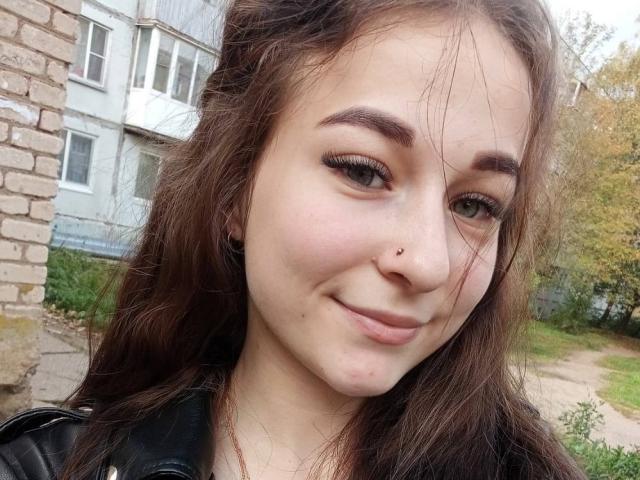 CherelleDelozier has long brown hair, a nose piercing, and is smiling with a slight smirk. She's wearing a black leather jacket and has dark eyeliner.