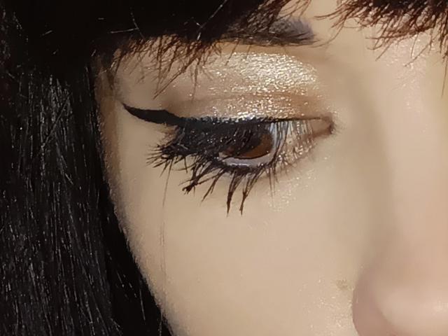 OrianaLaFrancaise's eye is a shiny, glossy brown with thick, black, dramatic eyelashes and a subtle, shimmering eyeshadow. Her dark, straight hair is partially visible.