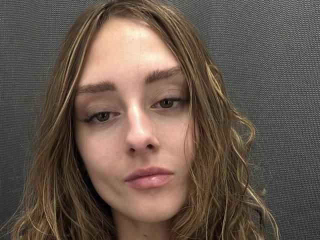 Lia a les cheveux bruns, ondulés et humides, une peau claire, des lèvres pleines et roses, et des yeux verts à demi-clos. Ses sourcils sont foncés et légèrement arqués. Elle regarde droit devant la caméra..