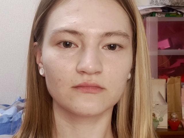Armandina Aumich tiene la piel clara, ojos marrones, cabello rubio lacio, pequeños audífonos blancos y algunos granitos en la cara, con una expresión neutra. Sus senos no son visibles..