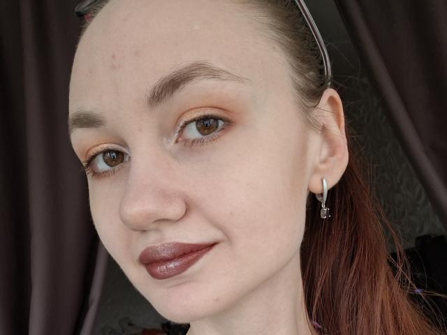 XSvibes heeft een lichte huid, bruine ogen en rode lippenstift met subtiele oranje oogschaduw. Ze heeft een neusring, kleine oorbellen en haar rode haar is naar achteren gebonden..