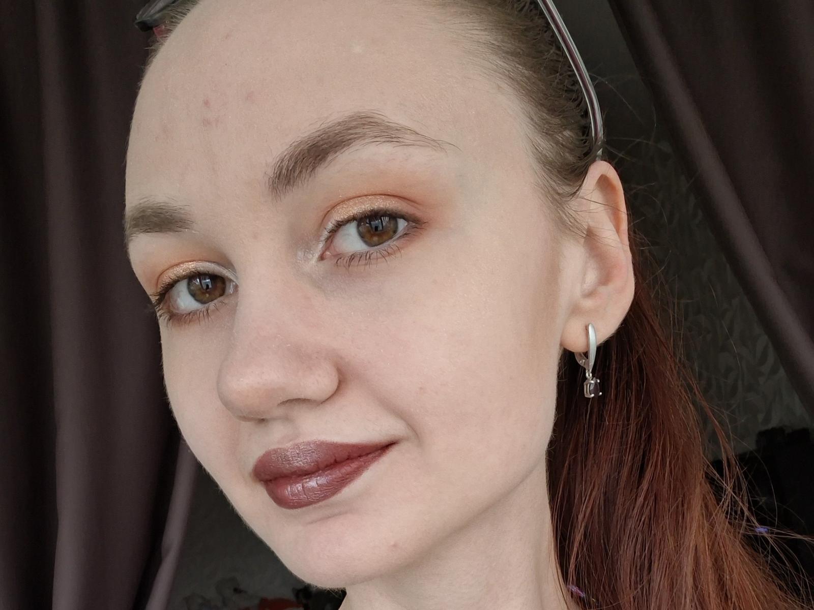 A XSvibes tem pele clara, olhos castanhos e batom vermelho com uma sombra laranja suave. Ela tem um piercing no nariz, brincos pequenos e o cabelo ruivo está preso..