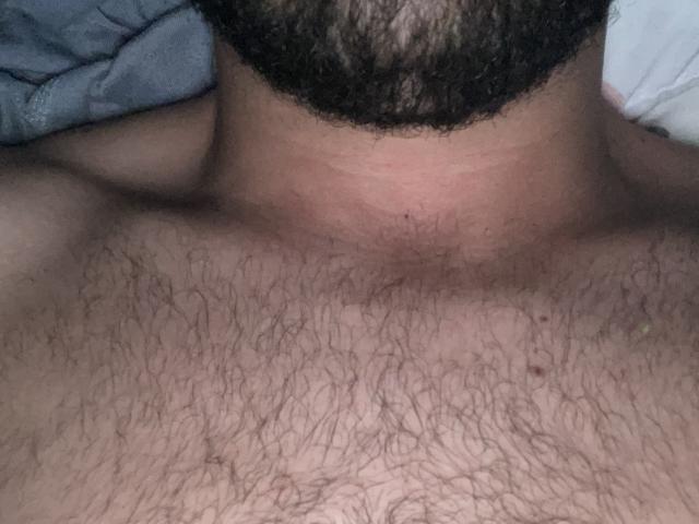 Keviago's hairy chest and neck with dark curly beard, showing a tan skin tone and dense chest hair. Image focuses on upper torso.