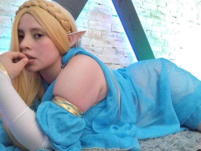 Nyxaria with blonde cosplay, elf ears, lying down, blue sheer dress, white arm, finger to lips, pouty expression, pale skin, blue eyes, flirty, cute, sexy.