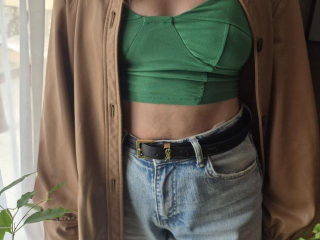 LoriEla's green bra-like top with small tits, tucked under a brown jacket, paired with high-waisted blue jeans and a black belt with a gold ring.