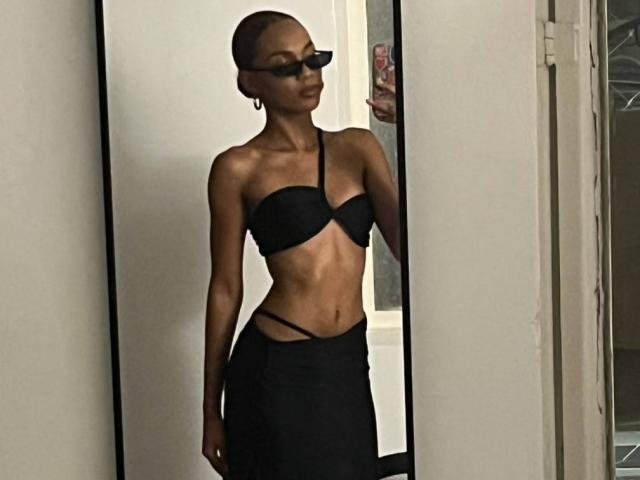 AylaCallowey is wearing a black strapless bra and a black skirt with cutout sides, standing with a slim, toned body, and dark sunglasses, looking confident.