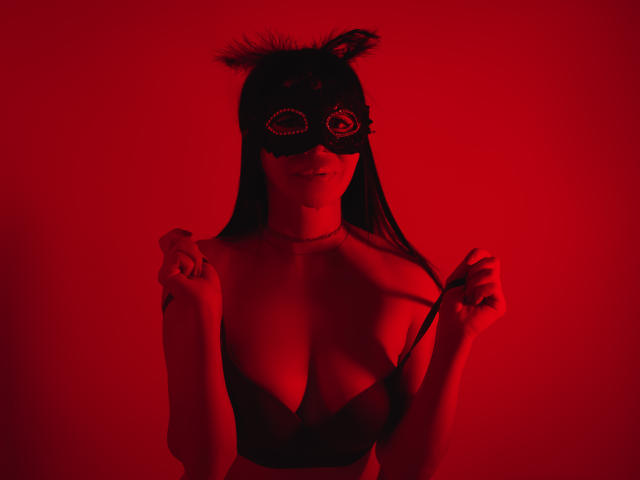 HelenHard with red mask, cat ears, black bra, pulling straps, showing tits, long hair, red light, holding straps, slight smile, looking forward, hands near chest.