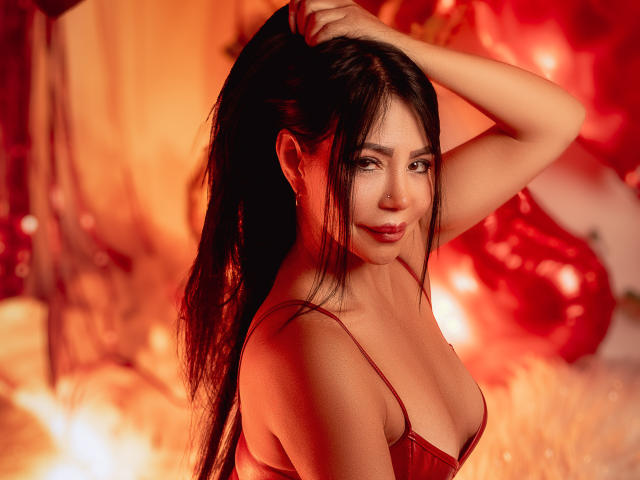 HelenHard with long black hair, red lingerie, and a sexy smile, holding her ponytail, showing her tits, in a fiery red-lit scene, looking sultry.