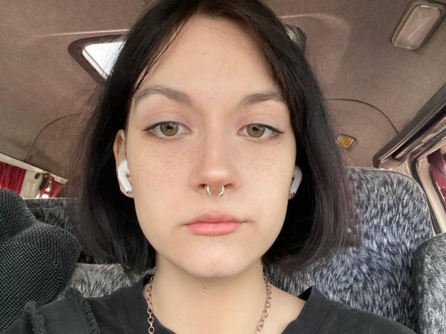 Rosenda Villaescusa tiene la piel clara, ojos marrones, cabello negro hasta los hombros, un piercing en la nariz, audífonos blancos y lleva una camisa negra con una cadena de plata. Está sentada en un autobús..