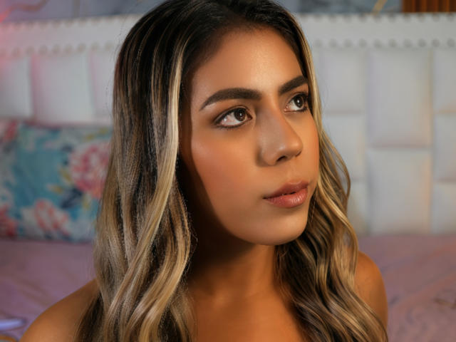 QuickHookup has medium brown skin, long wavy blonde-streaked hair, and brown eyes. Her glossy pink lips are slightly parted, showing a soft, sexy expression.