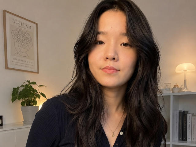 SamanthaTango with long, wavy black hair, wearing a black shirt, and a gold necklace, has a light skin tone and is making a slightly pouty expression.
