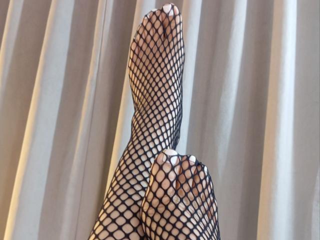 ChristineBray's feet in black fishnet stockings, toes pointing up, with her toes slightly curled, showing the net pattern over her skin.