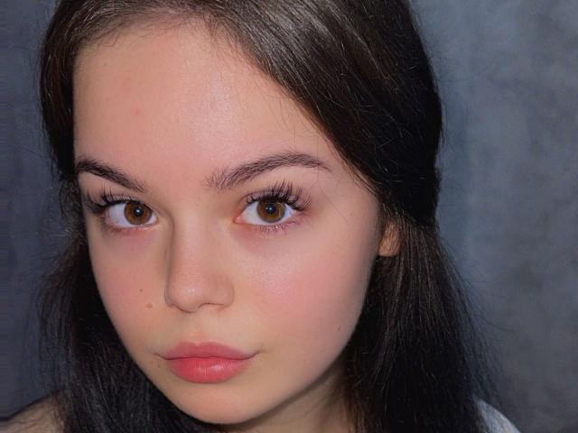 O rosto de Brandy Styer, com olhos castanhos, lábios rosados e cheios, pele clara e cabelo castanho escuro, olhando ligeiramente para o lado. Seu pequeno nariz e longos cílios são visíveis..