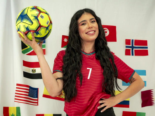 MiluSky with long black hair, smiling, wearing a red soccer jersey with a white number 7, holding a colorful soccer ball in her right hand.