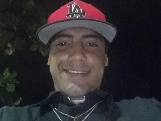 IvyTemptation, a chubby guy with a dark skin tone, wearing a red LA cap, smiling, showing a bit of his white tee under a dark jacket.