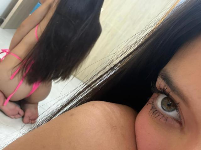 MichellFord's eye in the foreground, long brown hair, pink thong, and bare butt in the mirror, kneeling on white tile. Reflection shows her ass and thong.