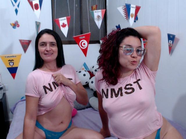 LunaVenus con cabello negro y LunaVenus con cabello rojo rizado, ambas usando camisetas rosas con la inscripción "NMST", levantando las camisetas para mostrar pequeños pechos, usando bombachas de encaje azules, haciendo pucheros..