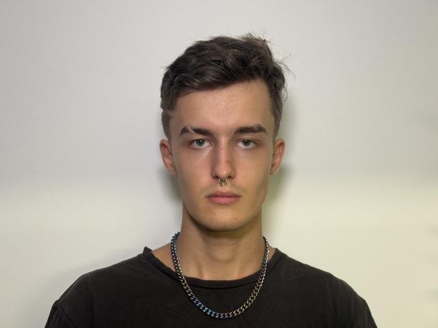 Manuel Landquist, met kort, donkerbruin haar, een neusring en een ketting, draagt een zwart shirt en heeft een serieuze blik..
