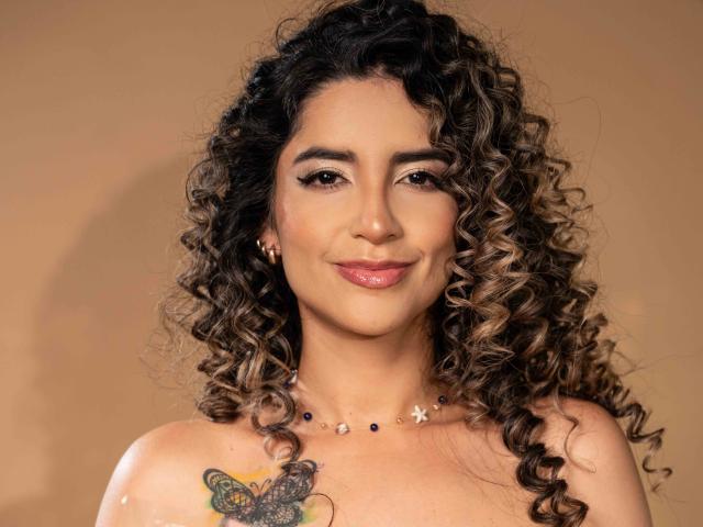 SofyaLane ha i capelli castano ricci, una carnagione media e un tatuaggio a forma di farfalla sul seno destro. Sorride, con il rossetto rosa, indossa una collana e ha degli orecchini dorati..