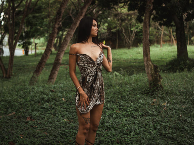 ShantellRuiz è in piedi in una foresta, indossa un vestito corto, con una spalla scoperta, a stampa leopardo, che mostra il seno e un tatuaggio sulla coscia, con lunghi capelli neri e un braccialetto..