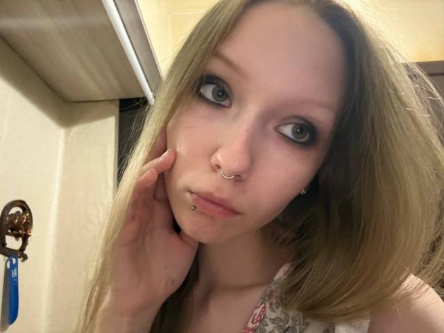 RendaPancake heeft lang blond haar, groene ogen en meerdere piercings in haar gezicht, waaronder een neusring en een lipring. Ze raakt haar wang aan met haar rechterhand..