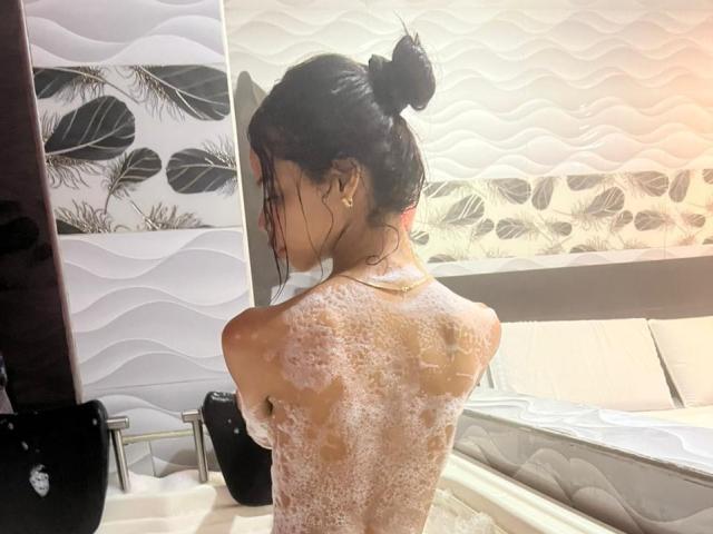 LiaBlom è sotto la doccia, bagnata e piena di sapone, con la schiena rivolta verso la telecamera, i capelli scuri raccolti in un disordine e la schiuma del sapone che le copre il seno e i glutei..
