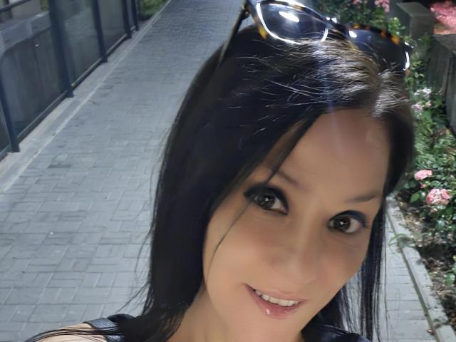 A JoliDanielle tem cabelo preto, olhos castanhos e um sorriso discreto. Ela está usando óculos de sol na cabeça, com os lábios ligeiramente entreabertos. Suas nádegas não estão visíveis..