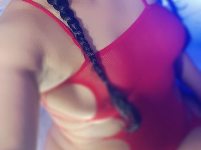 Le maillot de bain une pièce rouge, découpé et avec une ouverture sur le côté de FetishLoverAna, qui révèle son dos nu, bronzé et galbé, ainsi que son côté, avec une tresse noire qui pend..