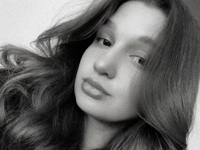 Black and white photo of MissKuromi with long, wavy hair, slightly tilted head, and pouty lips. Her eyes are half-open, and she has a subtle, sexy expression.