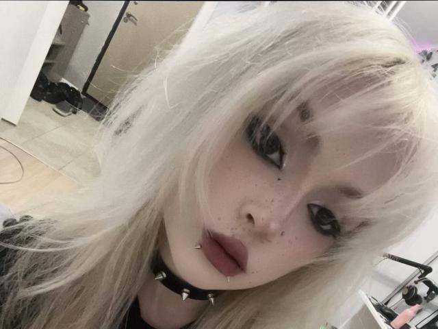 Hortencia Vergin, avec ses cheveux blond platine, son maquillage noir pour les yeux, ses piercings au nez et aux lèvres, et un collier à pointes, regarde l'appareil photo avec une bouche légèrement entrouverte et boudeuse..