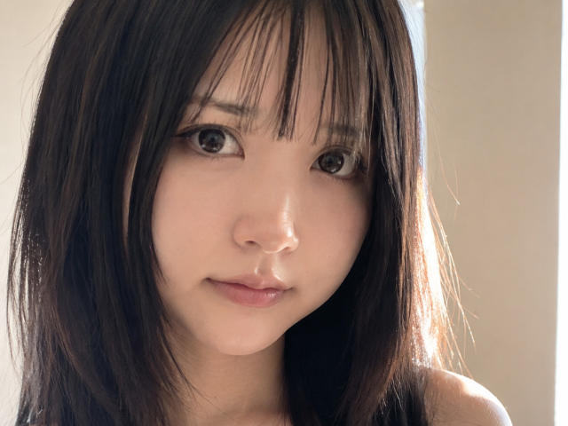 AnnettaHatchcock has straight black hair, bangs, and brown eyes. Her light skin, small nose, and slight smile are visible. She's looking at the camera with a subtle, cute expression.