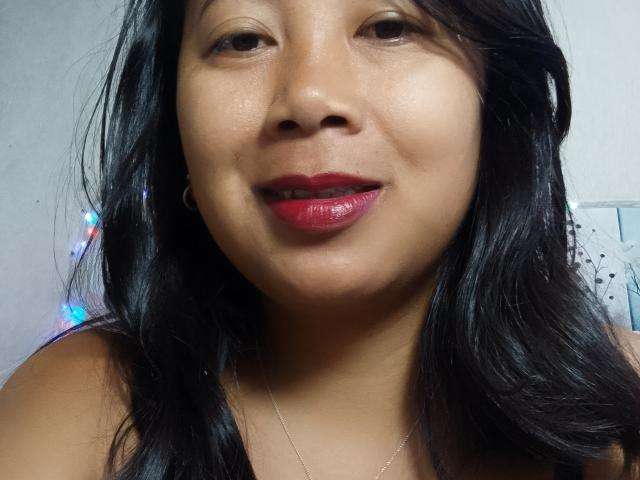 SarahFontaineX ha la pelle marrone media, i capelli neri e ondulati, il rossetto rosso e un sorriso discreto. Si possono vedere il suo naso piccolo e i suoi occhi marroni. Indossa una collana d'argento..