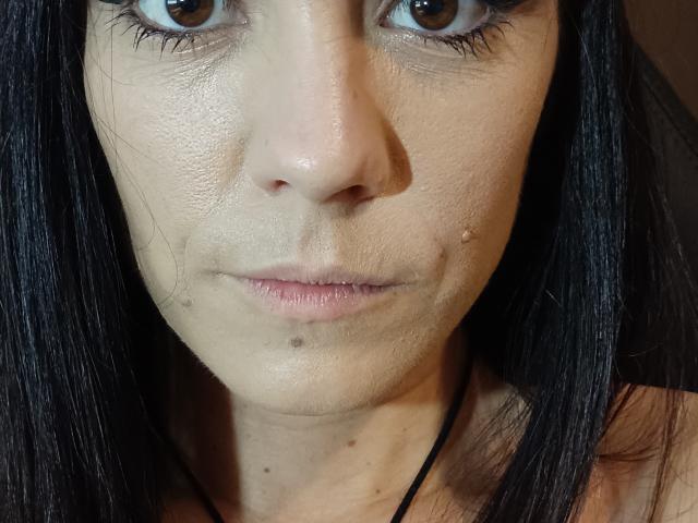 OrianaLaFrancaise ha un brufolo sul mento, una piccola macchia sotto il naso e un leggero cipiglio. Ha gli occhi marroni, i capelli neri e un viso leggermente lucido..