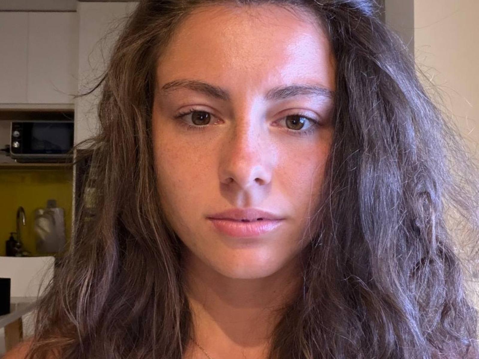 WillaBelz heeft lang, golvend bruin haar, bruine ogen en een neutrale uitdrukking met lichtroze lippen. Ze kijkt recht in de camera met een kalme uitstraling..
