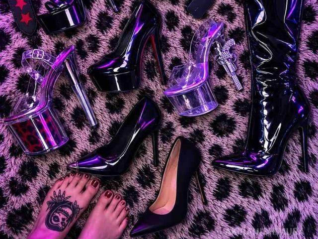 De glanzende zwarte pumps, leren laarzen, transparante sleehakken en roze stiletto's van AkiraNishimura69, op een tapijt met luipaardprint, met een getatoeëerde voet en rode teennagels..