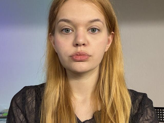 TanaHard ha la pelle chiara, gli occhi verdi e i capelli lunghi e rossi. Sta facendo la smorfia con le sue labbra rosa e indossa una maglia nera in pizzo. Il suo seno non è visibile..