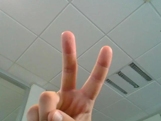 La mano de GeorgTest-hot formando un símbolo de paz con los dedos ligeramente separados, mostrando un tono de piel claro y limpio, sobre un fondo de techo blanco y liso..