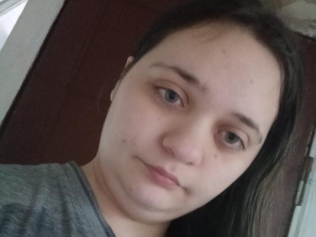 O rosto de Leonore Gerrie aparece na foto, mostrando pele clara, olhos castanhos e cabelo castanho liso. Ela está vestindo uma camisa cinza e tem uma expressão neutra..