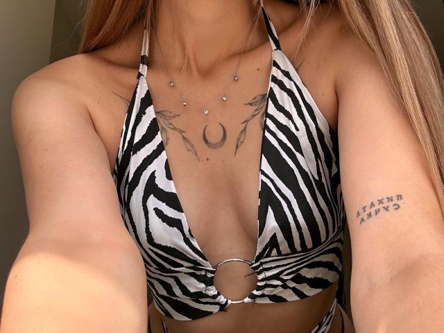 Le haut de maillot de bain rayé noir et blanc de Karish, qui met en valeur ses petites seins, a un anneau au centre. Elle a des piercings aux mamelons, un tatouage sous ses seins et un autre tatouage sur son bras..