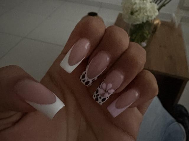 Las uñas de HikariChloe, con un diseño francés en rosa y blanco, presentan un estampado de leopardo y decoraciones de corazones rosas. Sus uñas son largas y brillantes..