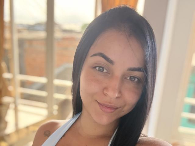HikariChloe tiene el cabello castaño oscuro, piel marrón clara, cejas gruesas, una nariz pequeña y una ligera sonrisa. Lleva una blusa azul claro, que muestra un pequeño tatuaje en su hombro..