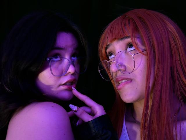 Deux personnes nommées AlexaNDRoss, portant des lunettes, dont l'une a les cheveux foncés et l'autre les cheveux roux, portant une veste noire, se touchant le visage sur une photo intime et sensuelle, éclairée en violet..