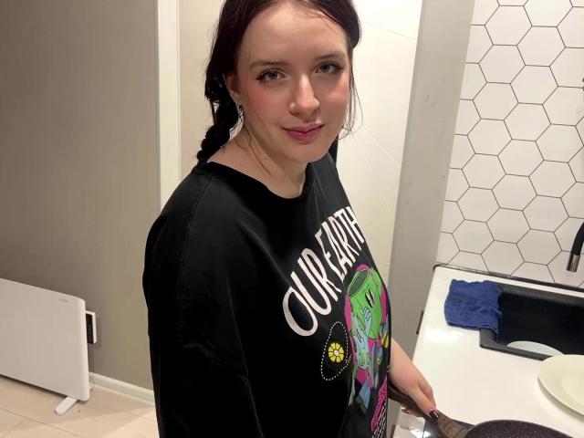 Candace Notaro, con i capelli rossi, indossa una maglietta nera con la scritta "Courage", rossetto rosa e orecchini, è in piedi in un bagno, tiene un asciugamano nero e sorride leggermente..