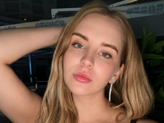 MollCharlyne heeft blond haar, blauwe ogen, roze lippen en een neusring. Ze draagt een zilveren oorbel en heeft haar arm omhoog. Haar borsten zijn niet zichtbaar..