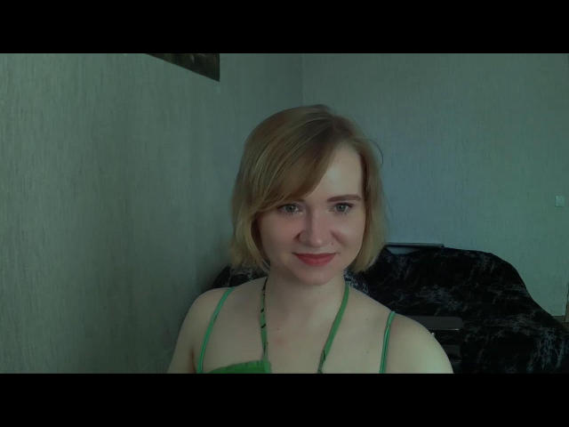 KaterinCold has short blonde hair, green halter top, and a cute smile. She's showing off her small tits with her green bra straps visible.