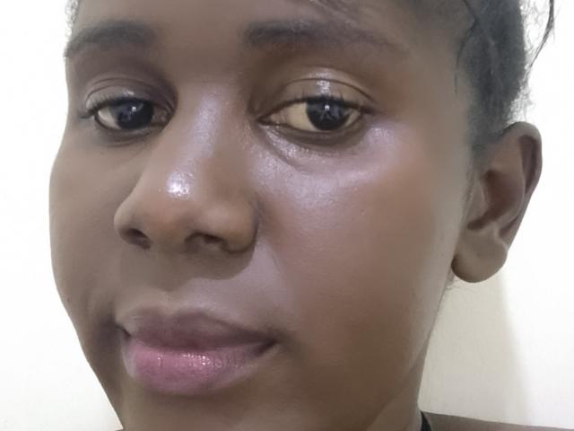 O rosto de MisLoh, com pele brilhante, olhos castanhos e lábios rosados levemente entreabertos. Ela tem cabelos escuros e cacheados e uma expressão neutra. A foto é um close-up..