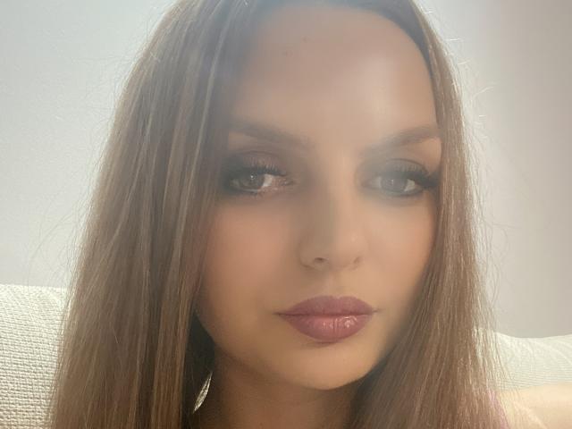 DouceAmelia ha i capelli castani lisci, labbra piene di colore rosa e occhi truccati in modo smokey con lunghe ciglia, che fissano direttamente la fotocamera con un'espressione neutra. La sua pelle è chiara e liscia..